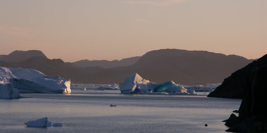 A photo of big icebergs floating in the sea at sunset