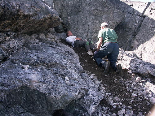 Two people digging and extracting from a blue sodalite vein