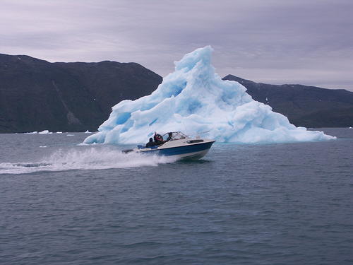A boat in front of a large iceberg 