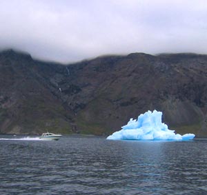 A boat in front of a blue iceberg