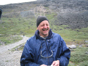A man laughing in front of a mountain