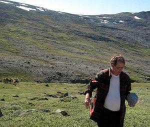 A person carrying a rock in front of a mountain