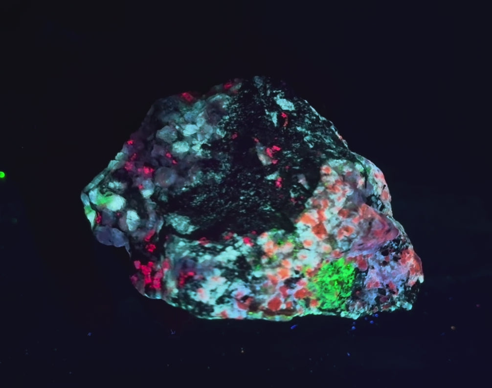 A piece of our highly sought after "Fantasy Rock". This piece features rich tugtupite that fluoresces a deep cherry red under shortwave UV.