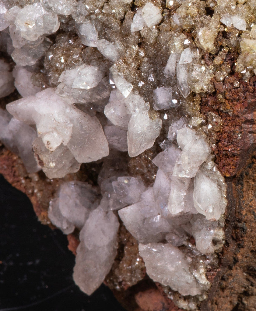 Sparkling, yellow-green, adamite crystals embedded in a limonite matrix along with larger, well-formed, white calcite crystals